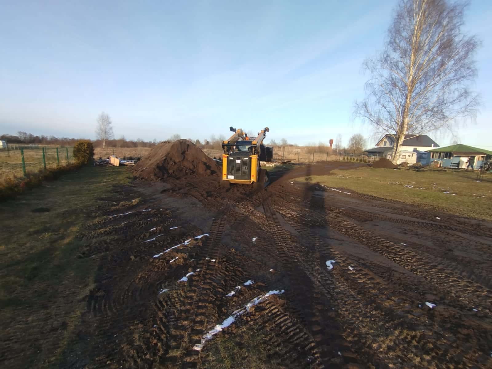 Grunts izlīdzināšana ar kāpurķēžu mini iekrāvēju pagalmā